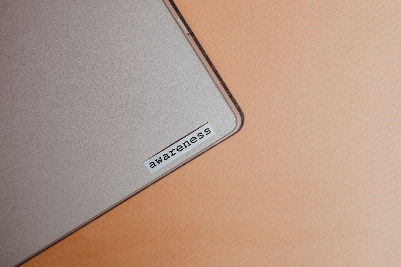 A detailed close-up of a beige laptop featuring an awareness sticker, highlighting mindfulness and digital organization.